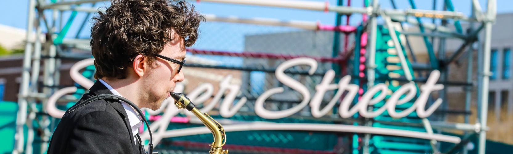 A saxophone player shot from the side in front of Sayer Street