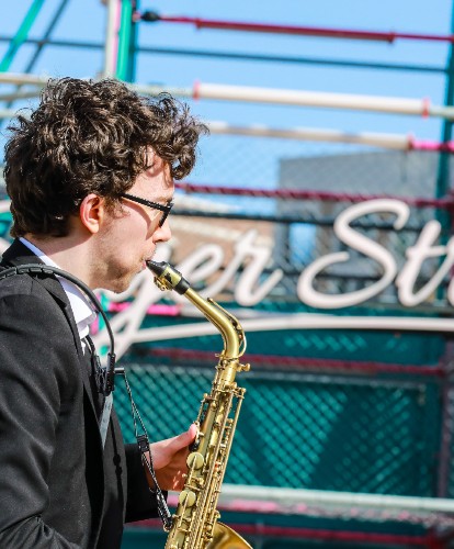 A saxophone player shot from the side in front of Sayer Street