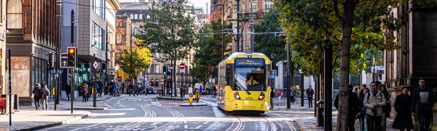 yellow tram next to pedestrians in Manchester City Centre