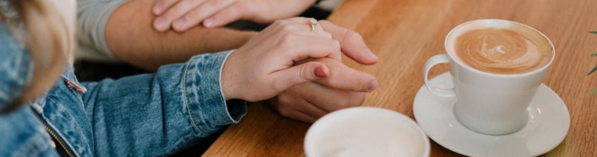 A couple holding hands next to coffees