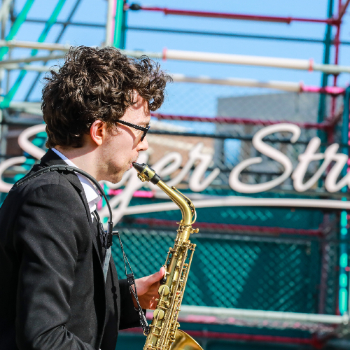 A saxophone player shot from the side in front of Sayer Street