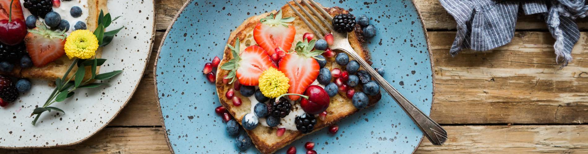 A plate of French toast with berries next to a cup of coffee