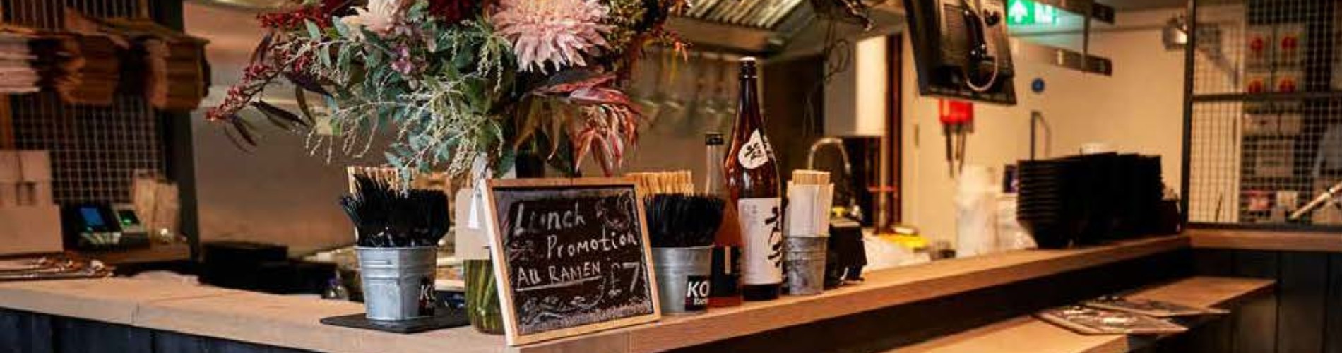 the interior of koi ramen bar and restaurant at elephant park. Sign on top of the counter saying "lunch promotion all ramen £7". Screen reader support enabled.