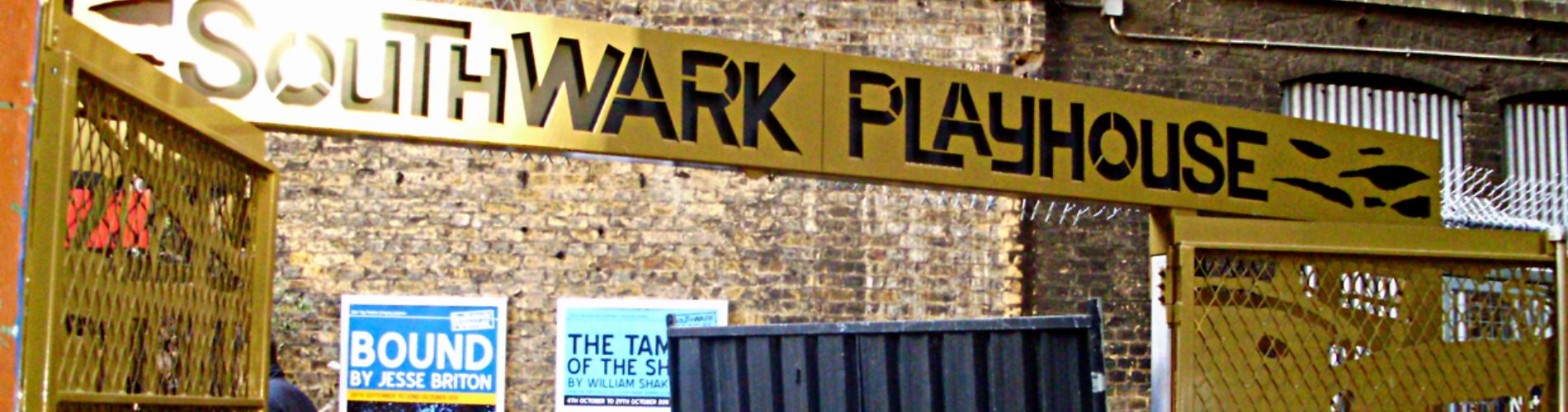 southwark playhouse sign hanging up over posters on a brick wall showing images of shows.