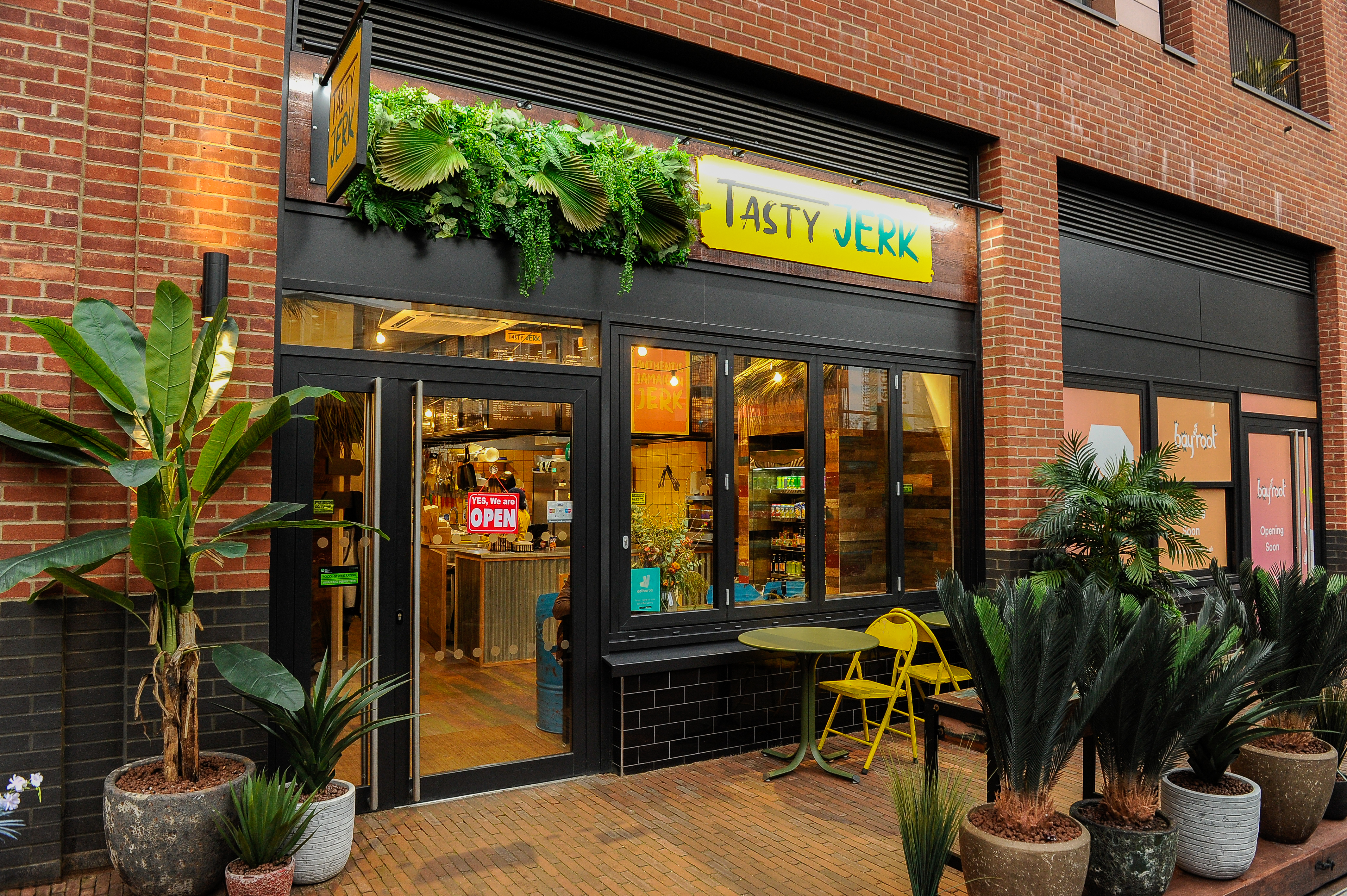 Exterior shop front of Tasty Jerk in Elephant Park surrounded by plants