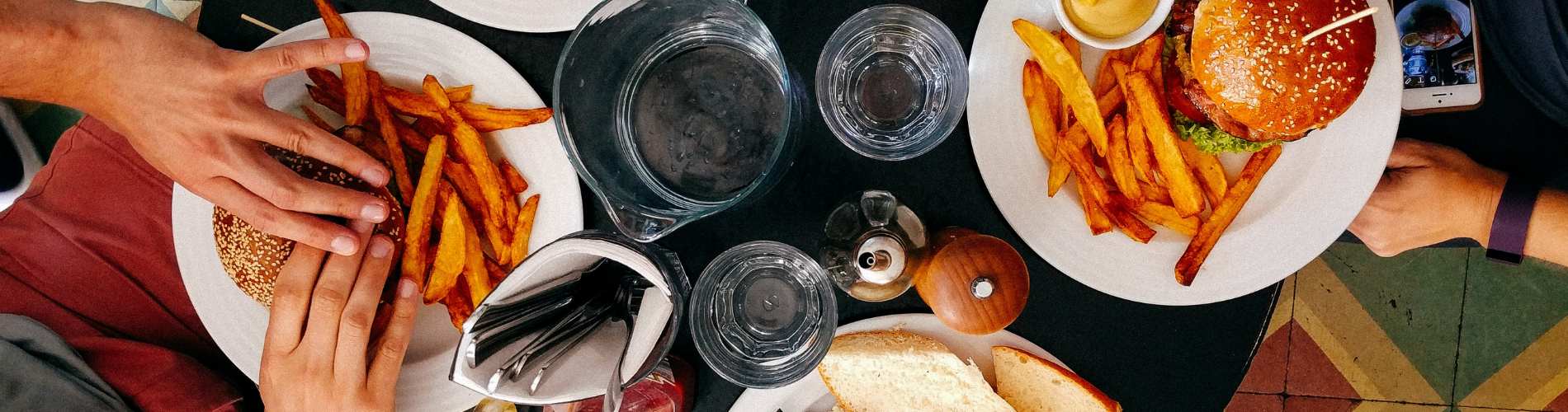 Four plates surrounded by people eating food
